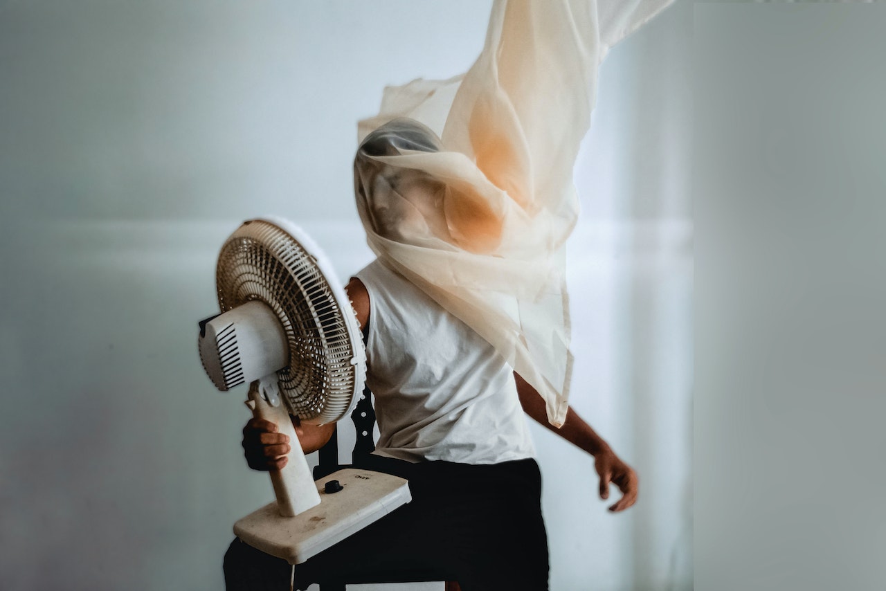 Man is cooling down his phone with help of a fan
