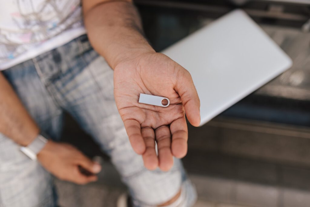 Young man is holding in his hand a tiny flash drive